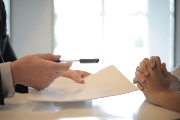 Hands passing over a pen during a contract consultation